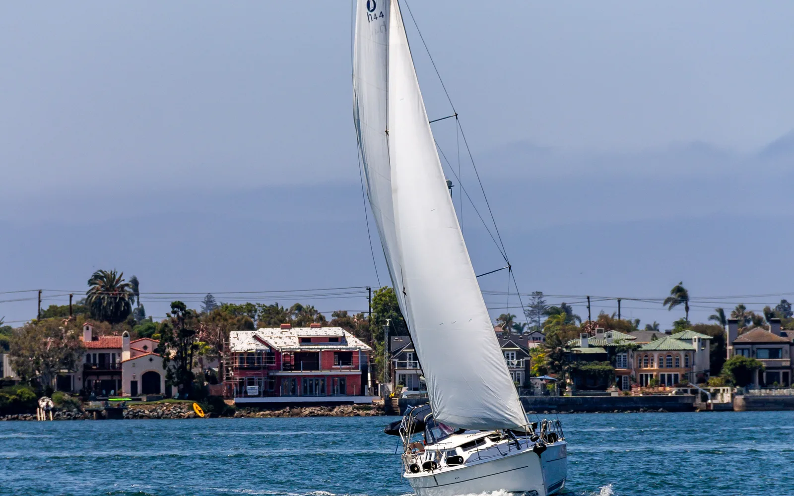 A sailboat on San Diego Bay with the city skyline and Coronado in the distance